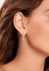 Zilveren creolen met een gebogen ontwerp en een verticale staaf die aan de creool hangt, met een gepolijste afwerking en strakke lijnen.