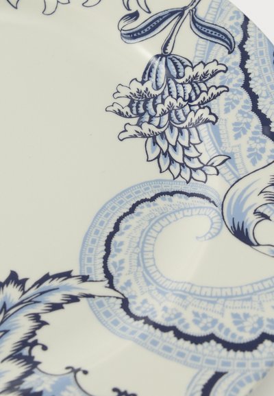 Assiette en céramique blanche ornée de motifs bleus complexes floraux et ressemblant à de la dentelle sur sa surface.