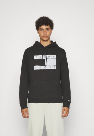 Sudadera negra con capucha que presenta un gráfico frontal con el texto "TOMMY JEANS" en blanco, cordones y un bolsillo tipo canguro; material de algodón suave.