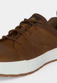 Brauner Ledersneaker mit braunen Schnürsenkeln und weißer Gummisohle, mit Markenlogo auf der Zunge und gepolstertem Kragen für Komfort.