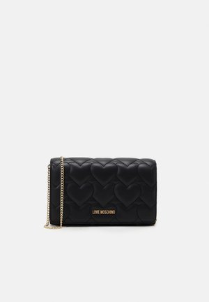 Sac noir matelassé avec motif cœur, bandoulière chaîne dorée et logo doré "Love Moschino" au centre avant.