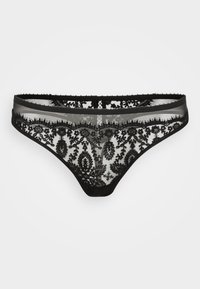 Thong en dentelle noire présentant des motifs floraux complexes, un tissu transparent, des bords festonnés et une taille lisse. Contraste avec le teint de la peau.