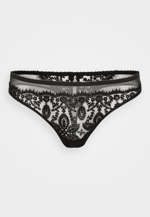 Svart spetsstring med intrikata blommönster, genomskinlig tyg, vågig kant och en slät midja. Kontrast med hudton.