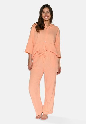Persikofärgade pyjamas i texturerad tyg. Har en knäppbar skjorta med två framfickor och byxor med resår i midjan.