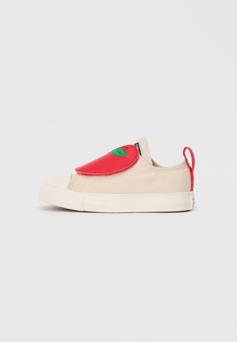 Basket beige pour tout-petit avec semelle blanche, rabat rouge en forme de pomme avec feuille verte sur le dessus, et languette rouge à l'arrière.