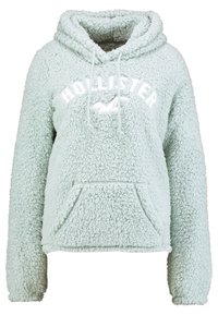 Mintgrön fluffig hoodie med en framficka, dragsko i huvan och vit "HOLLISTER" logotyp. Mjuk textur och avslappnad passform.
