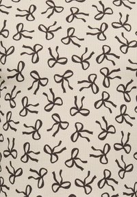 Prążkowana tkanina w kolorze kremowym z powtarzającym się wzorem małych czarnych kokardek. Wzór jest szczegółowy i równomiernie rozmieszczony na powierzchni.