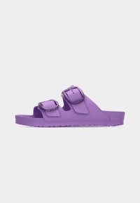 Μωβ σανδάλι slide με ανοιχτά δάχτυλα, δύο ρυθμιζόμενα λουριά με αγκράφες και υφασμένο πάτο, εμφανίζεται σε απλό φωτεινό φόντο.