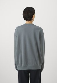 Grå sweatshirt med rund hals og lange ærmer, har en afslappet pasform med ribbede manchetter og kant for et struktureret udseende.