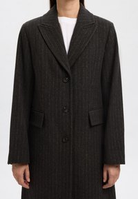 Mørkegrå, tyndstribet frakke med en hakket revers, enkeltbreddet knaplukning og to forlommer. Fremstillet af tekstureret stof.