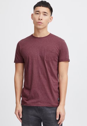 T-shirt bordeaux à manches courtes en tissu doux, avec un col rond et une poche poitrine, présentant une texture subtile et un ourlet droit.