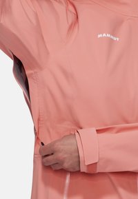 Wasserabweisende pinke Jacke mit glatter Textur, verstellbaren Ärmelbündchen und einem seitlichen Reißverschluss. Mit dem "Mammut"-Logo in Weiß.