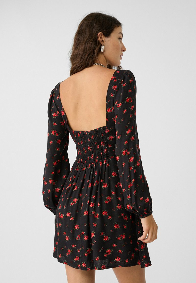 Schwarzes Blumenkleid mit roten Rosenmustern, langen Puffärmeln, gerafftem Mieder und einem tief ausgeschnittenen Rücken. Hergestellt aus leichtem Stoff.