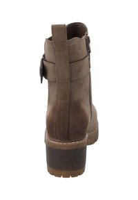 Stivale alla caviglia in suede marrone con punta tonda, tacco a blocco texturizzato, zip laterale e fascia decorativa con accento in fibbia metallica.