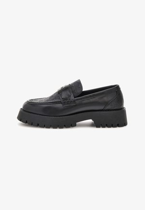 Loafer din piele neagră cu suprafață cu model, talpă chunky cu crampoane și detaliu cu bandă în partea de sus, prezentat în profil lateral pe fundal alb.