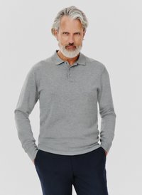 Szary długi rękaw polo wykonany z miękkiego materiału, z kołnierzykiem i plastronem na trzy guziki; noszony z ciemnonawowymi spodniami.