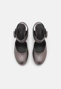 Scarpe in pelle verniciata grigio metallizzato con punta arrotondata e cinturino alla caviglia. La soletta nera testurizzata presenta un motivo a foglia. Dettaglio con fibbia regolabile.