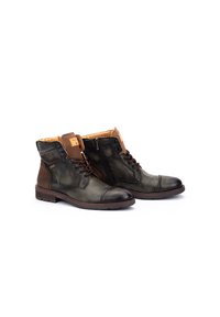 Botas de cuero marrón y verde con suela de goma, con cordones en la parte delantera y cremallera. Presentan una punta redondeada y acentos texturizados en los laterales.
