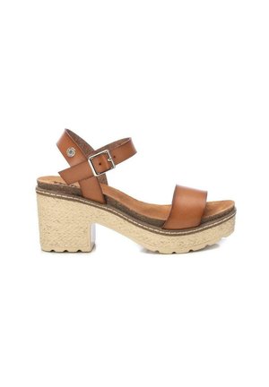 Sandalias de plataforma de cuero marrón con correa en el tobillo, tacón cuadrado y suela texturizada color crema. Presentan costuras mínimas y un acento metálico.