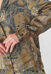 Bruine blouse met een paisley patroon, van zachte stof, met lange mouwen en knopenaccenten op de manchetten.
