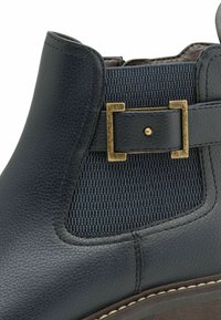 Ankle boot in dark blue leather with textured fabric panel, gold-tone buckle accent, smooth finish, and slight heel.