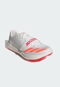 Baskets de course blanches avec des accents rouges, tige texturée, marquage "ADIZERO" bien en vue, et semelle extérieure rouge crantée pour une meilleure traction.