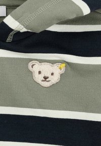 Gestreepte gebreide stof in tinten groen, marineblauw en wit; beschikt over een geborduurd berenhoofdpatch met een gele accent op het hoofd.