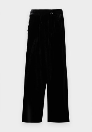 Zwarte fluwelen broek met brede pijpen, een hoge taille en een zijrits, weergegeven tegen een witte achtergrond.