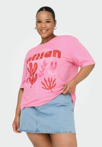 Camiseta de algodón rosa con texto rojo y gráficos florales, combinada con una falda de mezclilla azul claro. Mangas cortas y corte relajado.