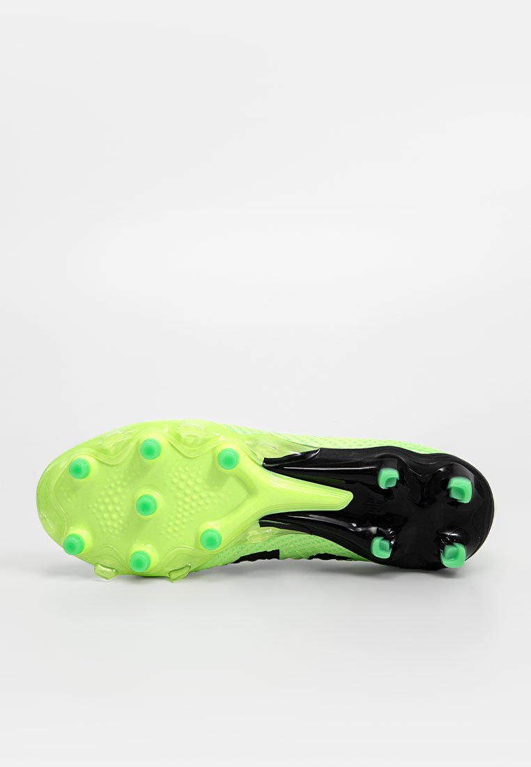 Bota de fútbol verde y negra con una parte superior texturizada, que presenta un diseño de perfil bajo y tacos moldeados para tracción en la suela.