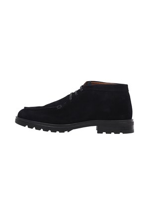 Bottines en suede bleu foncé présentant un bout arrondi, un laçage à deux œillets et une semelle en caoutchouc robuste avec des crampons proéminents pour une excellente traction.