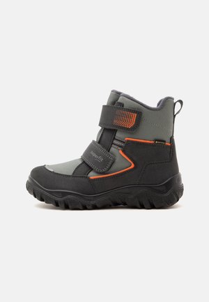 Stivale invernale per bambini grigio e nero con dettagli arancioni, due cinturini in velcro, suola robusta e etichetta Gore-Tex per impermeabilità e isolamento.