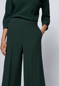 Gröna vida byxor i mjukt tyg med hög midja, sidofickor och en ren, skräddarsydd design.