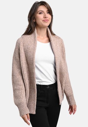 Knit cardigan in light beige with ribbed texture, open front, and wide sleeves. Worn over a white top and black pants.