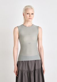 Haut sans manches gris clair en tissu lisse et extensible, conçu avec un col rond et une silhouette ajustée. Complète une jupe grise fluide.