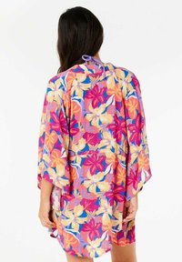 Farverig blomster kimono i pink, lilla, og gul, med en løs pasform, brede ærmer og bindelukning ved halsen.