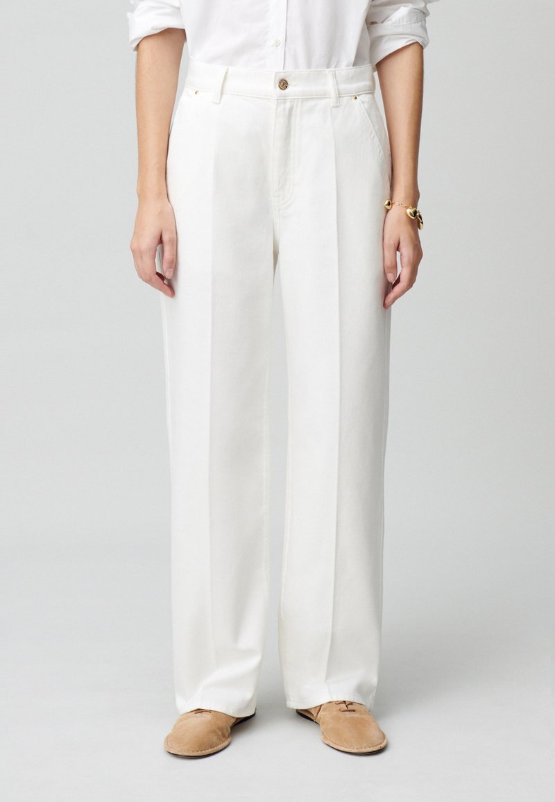 Pantaloni bianchi a gamba larga in cotone con vita alta, dotati di un bottone frontale, tasche laterali e una texture pulita e liscia.