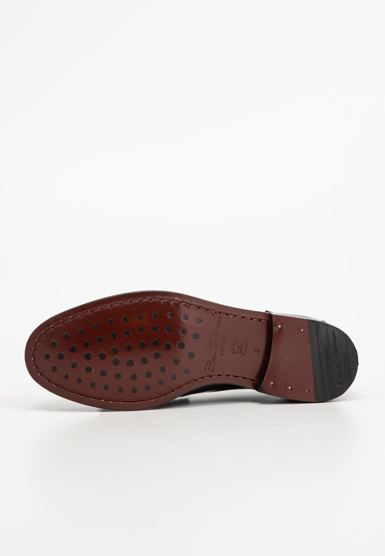Suola in pelle marrone scuro, caratterizzata da una finitura liscia, punta arrotondata e un motivo a perforazione circolare per la traspirabilità. Accento in gomma nera sul tacco.