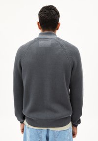Grauer Strickpullover mit hohem Kragen, gerippten Bündchen und Saum. Verfügt über ein strukturiertes Muster und Nahtdetails an den Schultern.