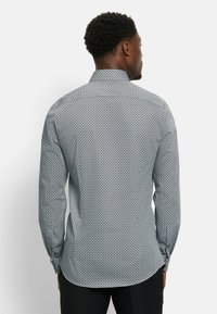 Herren Langarmhemd in Blau und Weiß mit geometrischem Muster. Verfügt über einen klassischen Kragen und Knopfmanschetten, hergestellt aus leichtem Stoff.