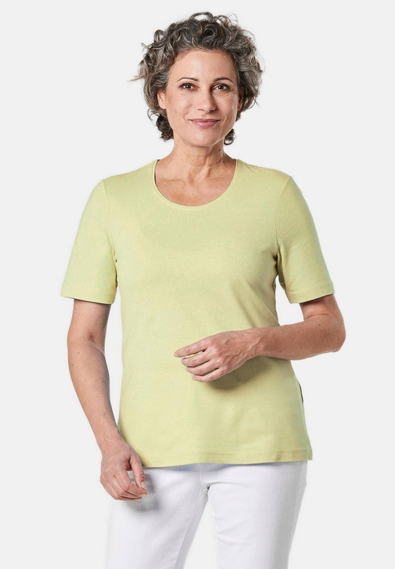 Helles gelbes T-Shirt mit kurzen Ärmeln und rundem Halsausschnitt, aus weichem Stoff, mit lässiger Passform und Seitenschlitzen für mehr Bewegungsfreiheit.