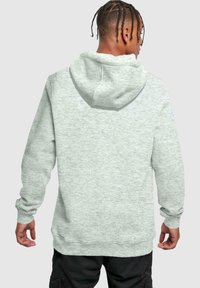 Sudadera gris claro de corte relajado, con capucha, mangas largas y puños acanalados. Textura suave y detalle de costura mínima.