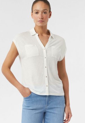 Witte korte mouwen blouse met knopen, voorzien van twee borstzakken en een ontspannen pasvorm. Zachte textuur met een lichte, luchtige uitstraling.