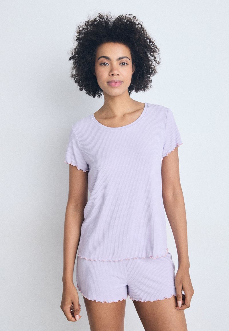 Ljust lavendelribbat pyjamaset med mjuka, scallopade kanter; kortärmad topp och matchande shorts. Slät yta, avslappnad design.