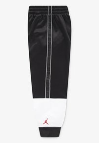 Sorte atletiske joggingbukser med en hvid stribe ved kanten og en vertikal grå stribe ned ad siden. Har et rødt logo på underbenet.