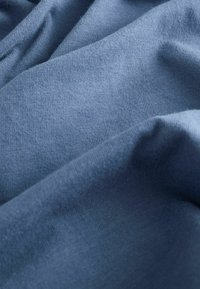 Tissu doux et texturé dans une teinte bleue profonde, légèrement froissé avec une finition lisse et un motif de tricot uniforme. Pas d'accents ou de matériel visibles.