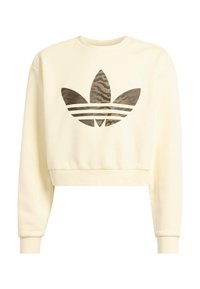 Kreminės spalvos trumpinta sportinė palaidinė su dideliu rudai juodu dryžuotu „Adidas“ logotipu priekyje. Minkšta tekstūra, ilgomis rankovėmis.