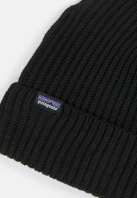 Μαύρο καλτσάκι πλεχτού με ραβδωτή υφή, που διαθέτει λογότυπο με βουνό σε μπλε, μωβ και κόκκινο χρώμα στη διπλωμένη άκρη.