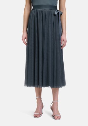 Gonna midi in tulle grigia con vita arricciata e nastro in satin. La gonna ha una texture trasparente e un design a strati, abbinata a tacchi argentati.