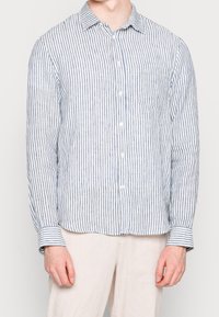 Chemise à manches longues rayée blanc et bleu marine, modèle boutonné avec une poche poitrine, tissu doux et poignets ajustables.